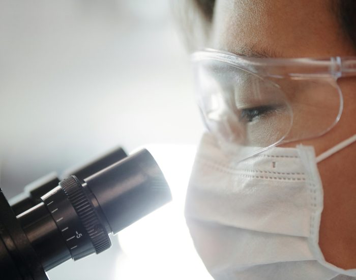 Close-up of a scientist wearing protective gear examining samples in a laboratory setting.